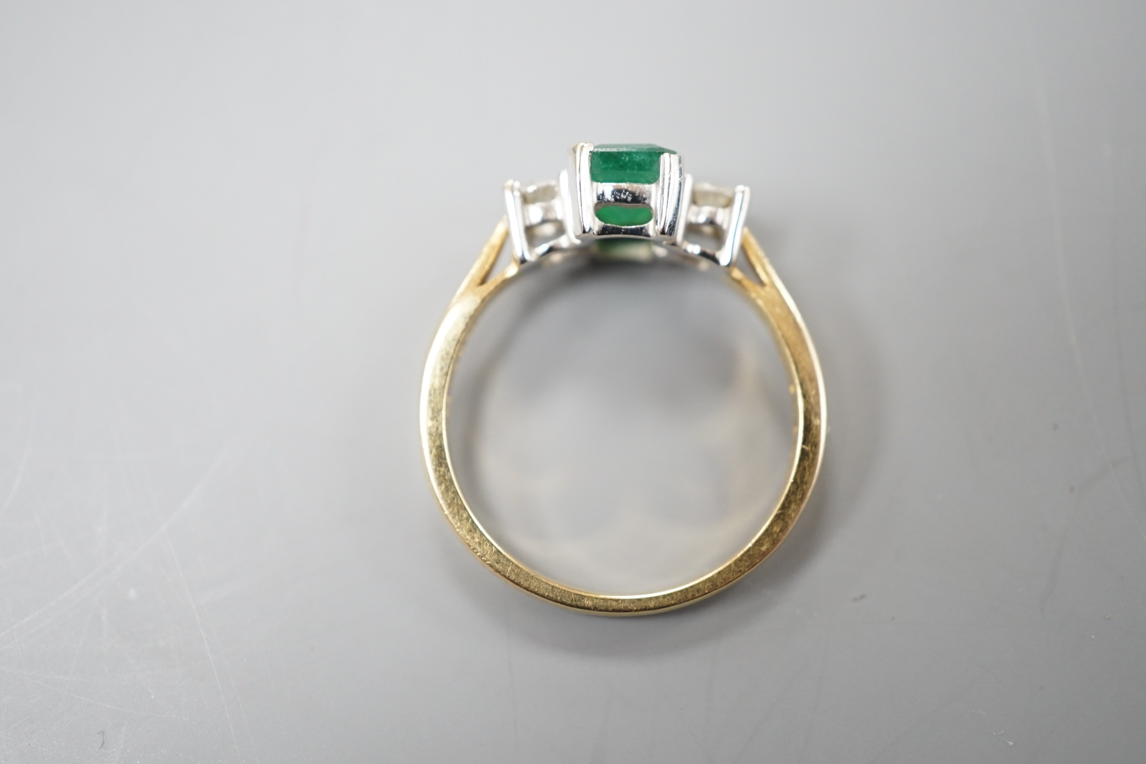 A modern 18ct gold, emerald and diamond set three stone ring, size N, gross weight 3.5 grams.